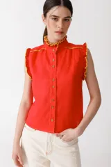 Blusa color mostaza sin mangas, con cuello alto y detalle de volados rojos en cuello, sisas y ruedo. Cierre frontal con botones.
