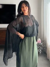 Poncho de hilo negro con diseño calado y flecos en el borde inferior.