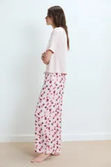 Pijama de dos piezas: remera rosa claro de manga corta con un pequeño bordado de labios en el pecho, y pantalón largo con estampado integral de labios en tonos rosados y bordó.