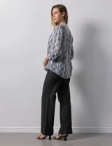 Blusa de gasa estampada con cuello a la base, escote en V y abertura central con botones. Delantera con plisados y mangas 3/4 regulables con presilla y botón.