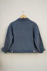 Campera de pana color rosa con botones dorados, cuello clásico y bolsillos con solapa en el pecho.