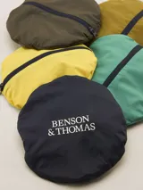 Gorro tipo bucket color mostaza con cinta decorativa a rayas horizontales en tonos bordó, amarillo y azul marino.