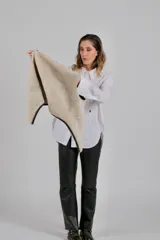 Chaleco reversible confeccionado en lambskin, con una cara de cuero en color marrón oscuro y otra de lana blanca. Presenta bolsillos frontales aplicados con ribetes de lana en contraste y diseño de cuello abierto.