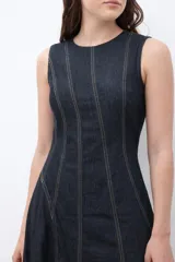 Maxi vestido sin mangas de denim oscuro, con corte al cuerpo en el torso y falda acampanada que cae hasta el tobillo. Presenta costuras visibles en contraste que definen los paneles del vestido.