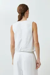 Chaleco blanco de lino con corte sastrero, cuello en V y cierre frontal con botones.