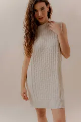 Vestido corto tejido color beige, sin mangas y con cuello redondo.