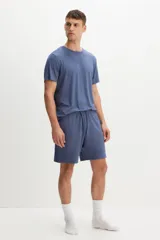 Conjunto de pijama azul de dos piezas en tejido de punto. Incluye una remera de manga corta con cuello redondo y un short con cintura elástica ajustable con cordón y bolsillos laterales.