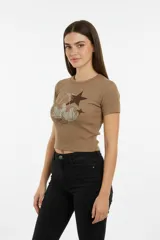 Remera de manga corta, corte al cuerpo, color marrón claro acanalado, con estampado frontal de cerezas con pedrería y estrellas marrones.