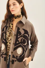 Campera manga larga color marrón con cuello camisero, confeccionada en gabardina con parches bordados en delantero y espalda.