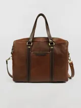 Maletín morral de cuero marrón con doble asa de mano, correa bandolera ajustable y bolsillo frontal. Ideal para laptop. Hecho en Uruguay.