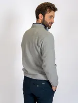 Sweater gris claro de tejido de punto con medio cierre frontal y cuello alto.