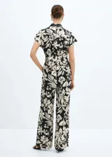 Mono largo de viscosa color crema con estampado floral fucsia, cuello camisero, manga corta, dos bolsillos laterales, trabillas y cinturón con lazo.