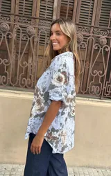 Camisa de algodón blanca con estampado floral en tonos tierra y verde oliva, manga corta y cuello camisero.