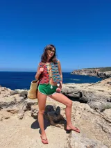 Chaleco tejido a mano en crochet con hilado 100% algodón, con diseño a rayas horizontales en tonos marrón, beige y blanco. Presenta terminaciones en color naranja y lazos del mismo color para cerrar en el frente.