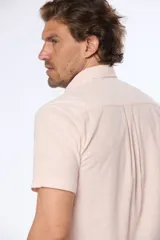 Camisa celeste de lino y algodón, de manga corta, con cuello abotonado y bolsillo en el pecho.