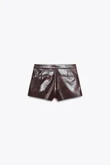 Shorts de tiro alto color marrón chocolate con efecto cuero. Presentan bolsillos laterales y falsos bolsillos de vivo en la espalda. Cierre frontal con cremallera y gancho metálico.