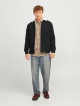 Sobrecamisa negra de manga larga con cuello clásico y fit relajado. Tiene cierre de botones, un bolsillo en el pecho y forro interno de borreguito color crema.