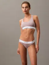 Conjunto de ropa interior Calvin Klein color lila, compuesto por un corpiño deportivo sin aro ni relleno, con espalda cruzada y banda elástica con logo, y una bombacha tipo tanga con cintura elástica con logo.