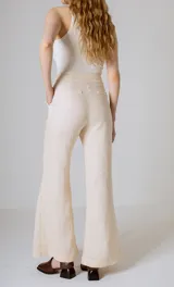 Pantalón de lino color beige, corte flare, tiro medio y costuras verticales al frente.