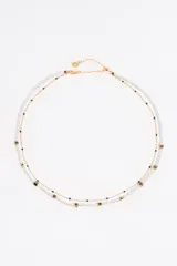 Collar doble con cadena dorada, uno con perlas de río y otro con cuentas de colores y dijes de letras.