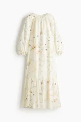 Vestido midi de corte amplio con estampado floral, cuello redondo con frunces, mangas globo 3/4 con puños elásticos, botones frontales y falda con volantes.