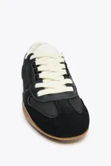 Zapatillas deportivas negras con detalle de estampado animal en la parte trasera, suela color caramelo y ajuste con cordones.