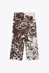 Pantalón de tiro alto con delantero cruzado y broche, con estampado floral en tonos marrones sobre fondo crudo.