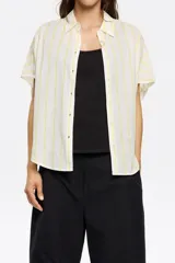 Camisa corta color crema de 100% algodón con cuello camisero y manga corta murciélago. Cierre frontal con botonadura.