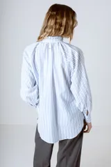 Blusa celeste con rayas verticales blancas, cuello mao y mangas largas abullonadas con puños elásticos.