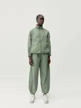 Pantalón estilo paracaídas color verde claro, de tejido técnico Wind_S, con bolsillos laterales y reguladores en la cinturilla y en el bajo.