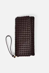 Bolso alargado color borgoña con diseño trenzado, asa bandolera y tirador con pulsera de mano. Incluye bolsillo interior, cierre mediante solapa y botón imantado.