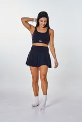 Conjunto deportivo negro compuesto por un top con logo "bk." y una falda corta con short interno.