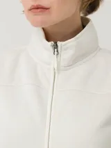 Chaleco micropolar color crudo, con cierre frontal completo, cuello alto y bolsillos laterales con cierre. Confeccionado con fibras recicladas.