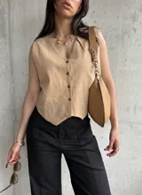 Chaleco color tostado de lino liviano con bordado de palmeras en la terminación y corte recto. Cierre frontal con botones.