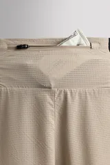 Shorts deportivos marrones de tejido técnico ligero y elástico con diferentes estructuras. Tiene forro interior, cintura elástica ajustable con cordón, bolsillos frontales, bolsillo trasero con cierre, aberturas laterales y logo estampado en la pierna.