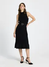 Vestido midi tejido negro con cuello alto, sin mangas, calado y falda con volantes. Incluye cinturón con hebilla irregular.