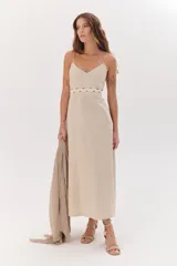 Vestido largo color beige de lino y algodón, con breteles finos y escote en V. Tiene cintura marcada con un galón ondeado de algodón y falda de línea A.