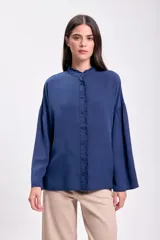 Blusa azul oscuro con cuello mao y volados en el frente. Mangas largas abullonadas.