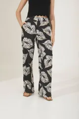 Pantalón sastrero con estampado de hojas en colores negro, blanco y beige, de corte recto.