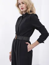 Mono largo negro con cuello y solapa, manga larga con puño de doble botón, dos bolsillos laterales y dos bolsillos de plastrón en el pecho. Cierre frontal con cartera oculta.