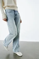 Jeans de tiro bajo, corte recto y largo completo, con efecto lavado y detalles de rotos en el delantero. Cierre frontal con cremallera y botón, y diseño de cinco bolsillos.
