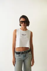 Musculosa blanca cropped de algodón con cuello redondo y estampa frontal con texto en negro.