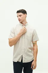 Camisa de manga corta color beige claro, confeccionada en lino y algodón, con fit regular y logo bordado en el pecho.