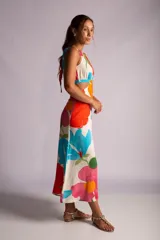 Vestido largo con estampado de flores en tonos naranja, rojo, verde y celeste. Tiene escote halter, espalda descubierta y aberturas en la cintura.