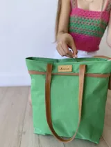 Bolso de lona color negro con detalles en cuero marrón, con bolsillo interno y forro de tela.