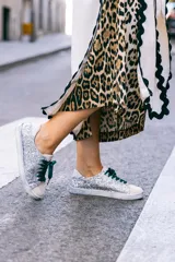 Zapatillas urbanas plateadas con glitter, puntera y talón en cuero blanco, cordones de raso verde esmeralda y suela blanca.