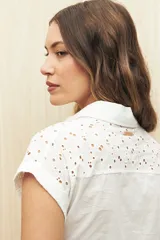 Camisa negra con broderie, de manga corta, calce relajado, cuello clásico, abotonada al frente y con lazo regulable en la cintura.