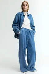 Pantalón denim celeste de corte holgado, con cintura elástica, cordón ajustable, bolsillos laterales y piernas anchas.