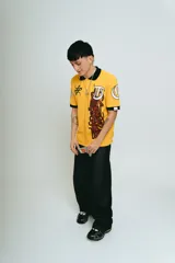 Chomba amarilla de piqué con cuello y puños negros, corte regular, bordado y aplique premium.