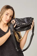 Bandolera negra de cuero vacuno con correa regulable de cinta, forrada en tela de algodón, cierre central y bolsillo con cierre atrás.